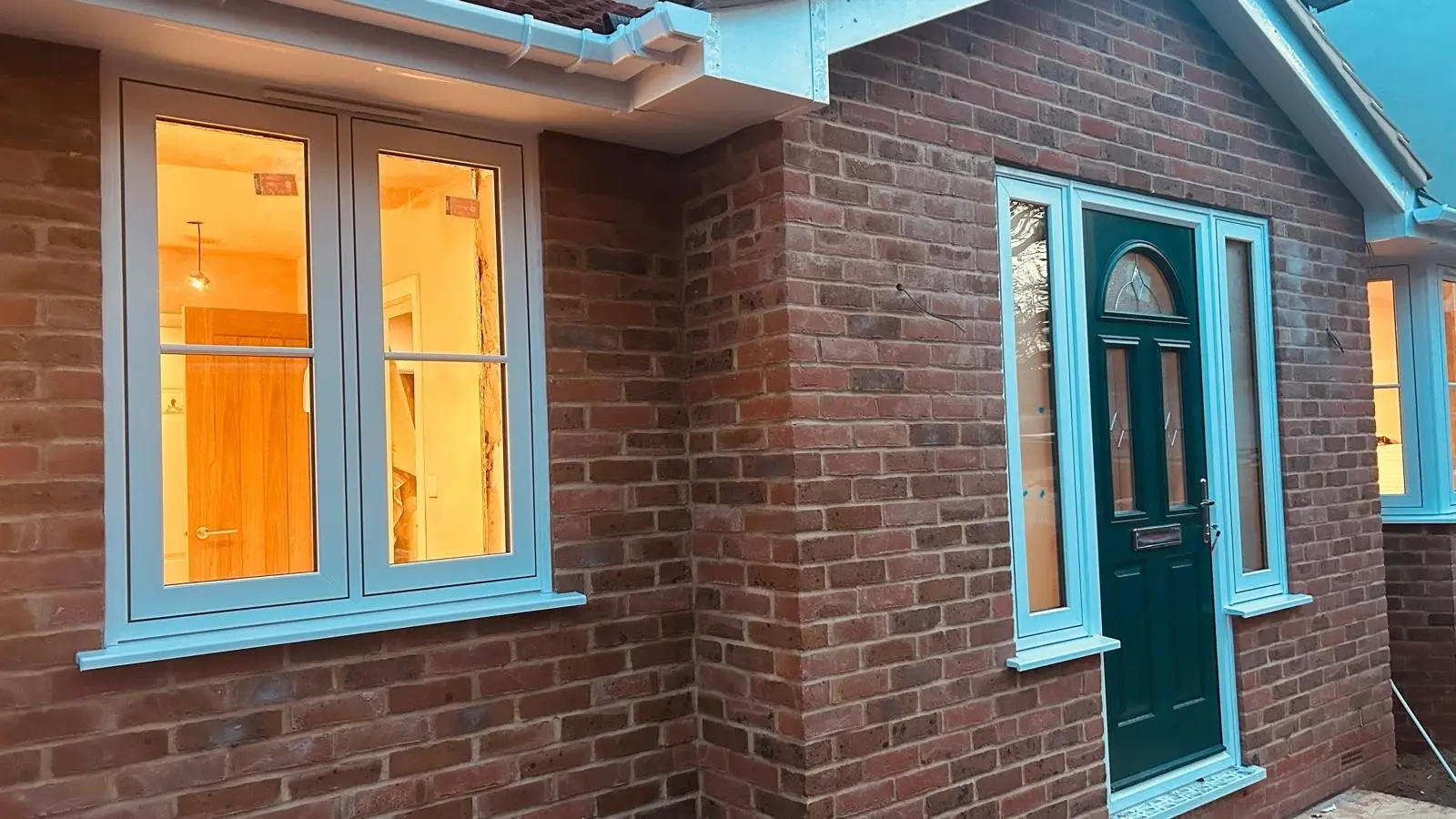 Teal-framed windows and a green composite door